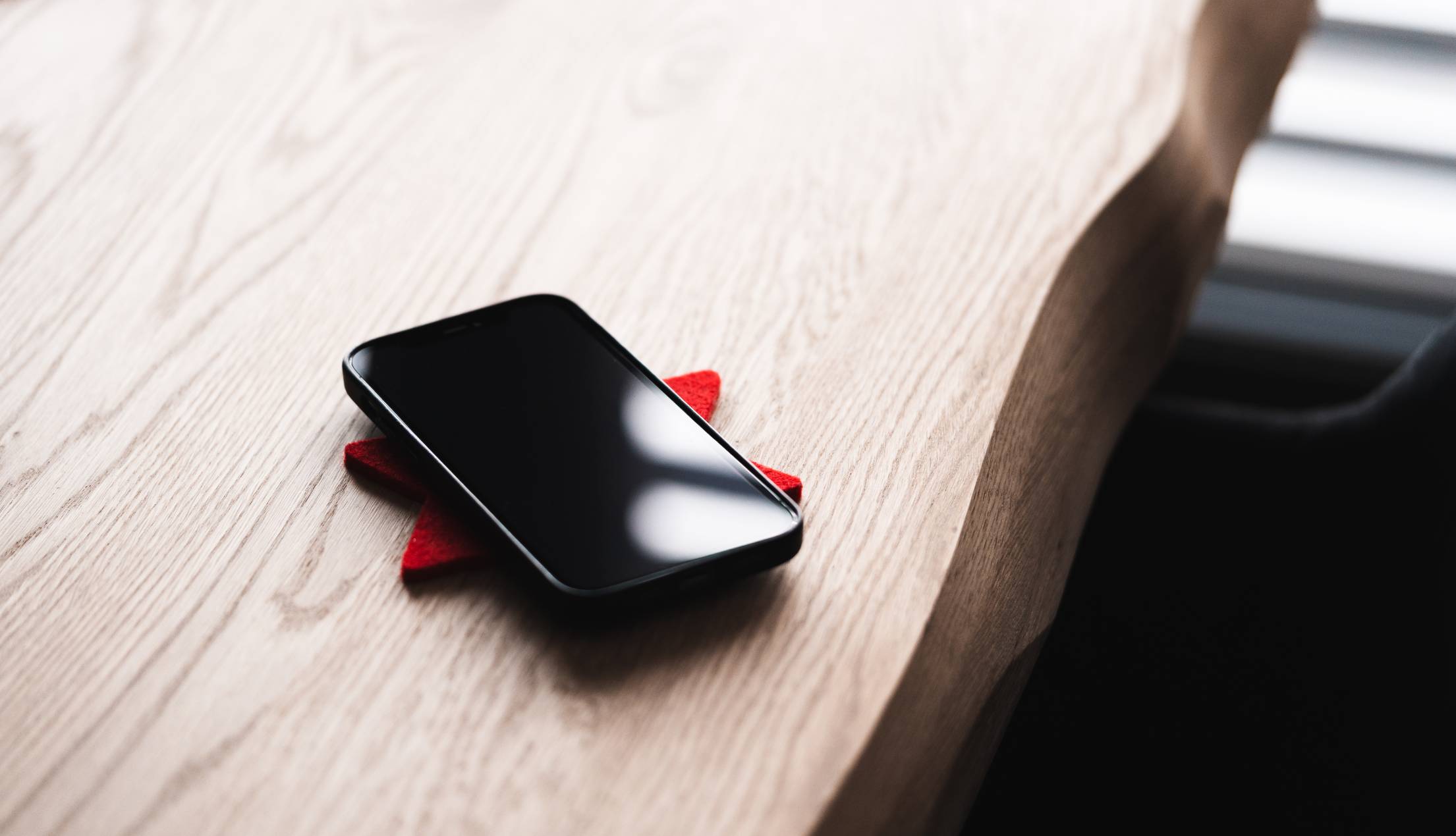 black-smartphone-lying-on-a-wooden-table-free-photo.jpg